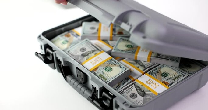 Female hands open briefcase full of stacks of dollar bills