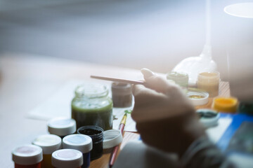 Woman's hand dips a brush in paint