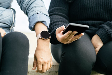 two Latina women are displaying their new smartwatch and smartphone