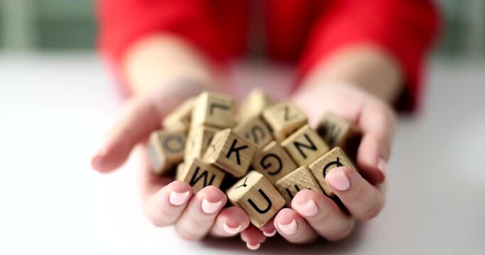 Female hands hold a pile of wooden cubes with letters closeup