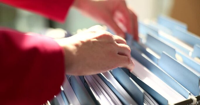Woman hands on folders with documents in archive