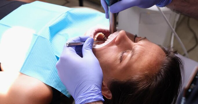 Dentist treats teeth to female patient in clinic