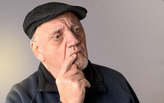 portrait vieil homme avec béret songeur expressif sur fond gris