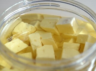 Pieces of cheese in oil. Glass jar of tasty brinza cheese. Recipes with cheese