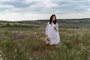Fototapeta na wymiar Chamomile woman. Happy curly woman in a chamomile field, dressed in a white dress.