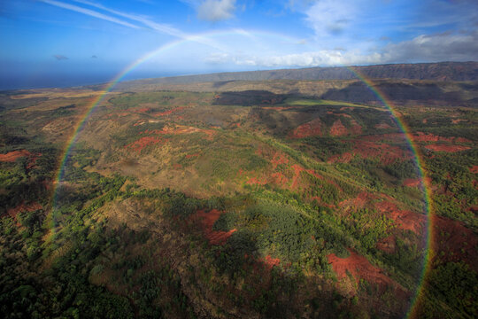 A full circle rainbow hovers over the Hawaiian landscape.
