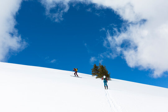 Sky and clouds over two skiers on snowcapped hill, Leadville, Colorado, USA