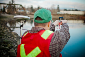 A Field Technician takes a bearing with his compass and collects data with a GPS unit.