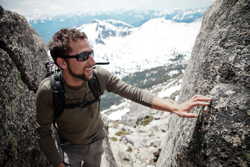 A backpacker cracks a snile after climbing past a crux section.