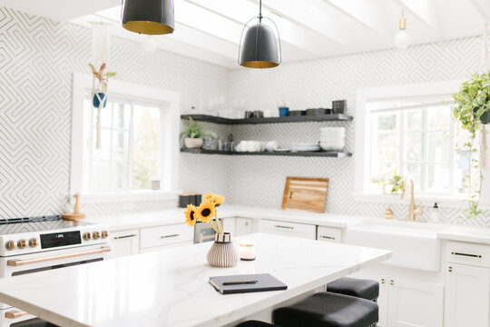 Bright white and black modern kitchen with notebook on counter