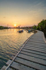 Obraz premium A wooden bridge built at the mouth of a river where there is a mangrove forest while sunset.