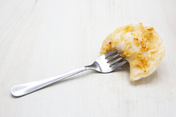 Pierogi or pyrohy or varenyky ( dumplings ) or vareniki with fried onions impaled on a fork...