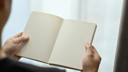 Over shoulder view of hands holding a blank opened notebook. Copy space for your advertise text