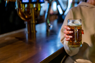 woman holds a glass of beer in his hand at the bar or pub