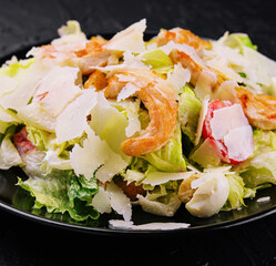 Delicious fresh caesar salad on black plate