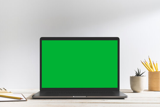 Chroma key green screen laptop on table with white background.