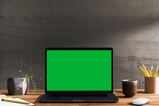 Chroma key green screen laptop on table, working space.