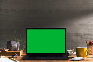 Chroma key green screen laptop on table with creative tools