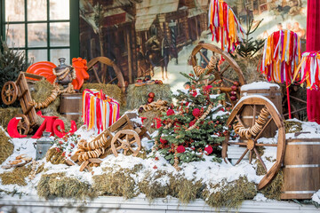 Fototapeta na wymiar Decorations on Tverskaya Street in honor of the celebration of the traditional Russian holiday Maslenitsa. Carts, hay, barrels, samovars, bagels and trees with colorful ribbons.