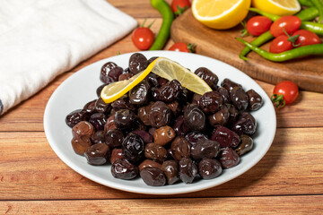 Black olive. Fermented olives and lemon slice in plate. Mediterranean flavors
