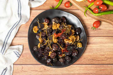 Mixed olives. Dried tomatoes, thyme, rosemary, walnuts and olives on the plate. Mediterranean flavors. Top view