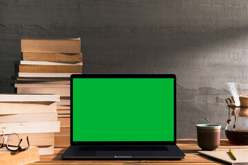 Chroma key green screen laptop on table with pile of books