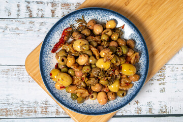 Mixed green olives. Green olive salad on wood background. Mediterranean flavors. Top view