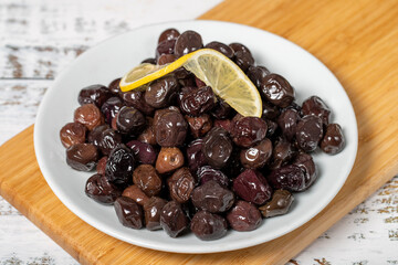 Black olive. Fermented olives and lemon slice in plate. Mediterranean flavors