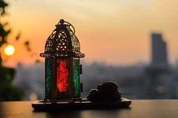 Lantern and dates fruit with dusk sky and city background for the Muslim feast of the holy month of...