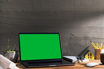 Chroma key green screen, angled view laptop on table with architectural tools