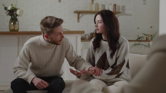 A family psychologist calms a young couple who share their experiences too emotionally. Husband and wife are trying to find a common language at the reception of a family psychologist.