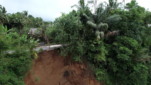 Landslide destroyed part of the road and created a dangerous situation, camera flies up showing the edge of the break. The aftermath of heavy rains and a small earthquake, central Bali