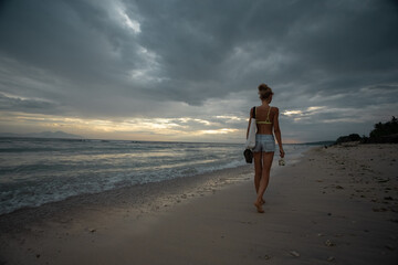 Traveler girl walking on tropical beach in sunset. Nusa Penida, Indonasia