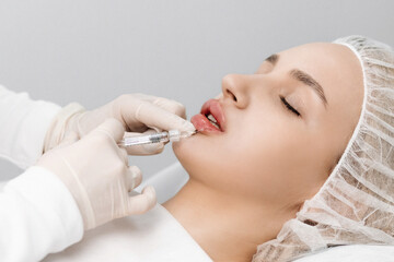 close-up, female lips. Surgeon, in medical gloves, carefully and slowly injects hyaluronic acid...