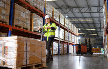 Fototapeta premium Worker in auto parts warehouse use a handcart to work to bring the box of auto parts into the storage shelf of the warehouse waiting for delivery to the car assembly line