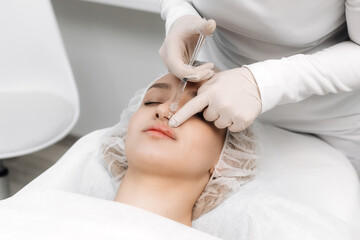 close-up, female lips. Surgeon, in medical gloves, carefully and slowly injects hyaluronic acid...