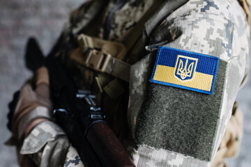 Ukrainian soldier wearing military uniform with flag and chevron depicting trident - Ukrainian...