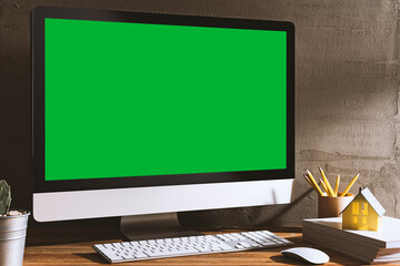 Chroma key green screen, angled view computer on table with white cover magazines and model house.