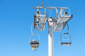 Ski chair lift over blue sky. Ski lift empty ropeway on hilghland mountain winter. Ski chairlift cable way with people enjoy skiing and snowboarding
