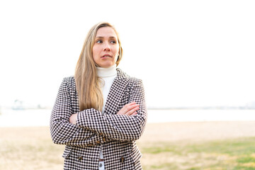 Young blonde woman at outdoors with confuse face expression