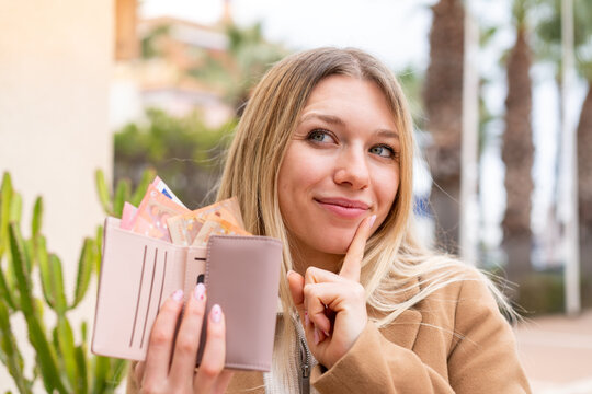 Young woman taking a lot of money and holding a wallet