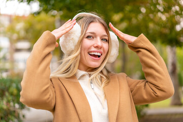 Young pretty blonde woman wearing winter muffs at outdoors with surprise expression