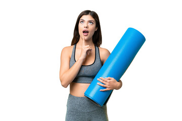 Young sport woman going to yoga classes while holding a mat over isolated chroma key background intending to realizes the solution while lifting a finger up