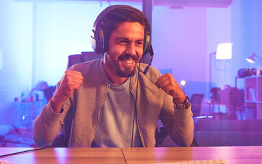 Winner, wow or man gamer on computer with microphone celebrating game win and success fist. Happy,...