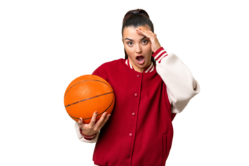 Young Woman playing basketball over isolated chroma key background doing surprise gesture while looking to the side