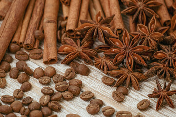 Fototapeta na wymiar Background with cinnamon sticks, anise stars, coffee beans and nuts. Spicy trendy background. Close-up of various spices on wooden table top view