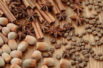 Obraz na płótnie Canvas Background with cinnamon sticks, anise stars, coffee beans and nuts. Spicy trendy background. Close-up of various spices on wooden table top view