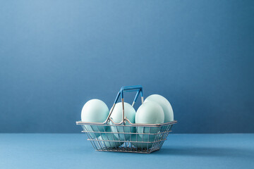 Several blue dyed Easter eggs in metal basket on table. Monochrome on blue. Easter holiday eggs...