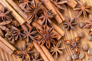 Background with cinnamon sticks, anise stars, coffee beans and nuts. Spicy trendy background. Close-up of various spices on wooden table top view