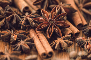 Background with cinnamon sticks, anise stars, coffee beans and nuts. Spicy trendy background. Close-up of various spices on wooden table top view